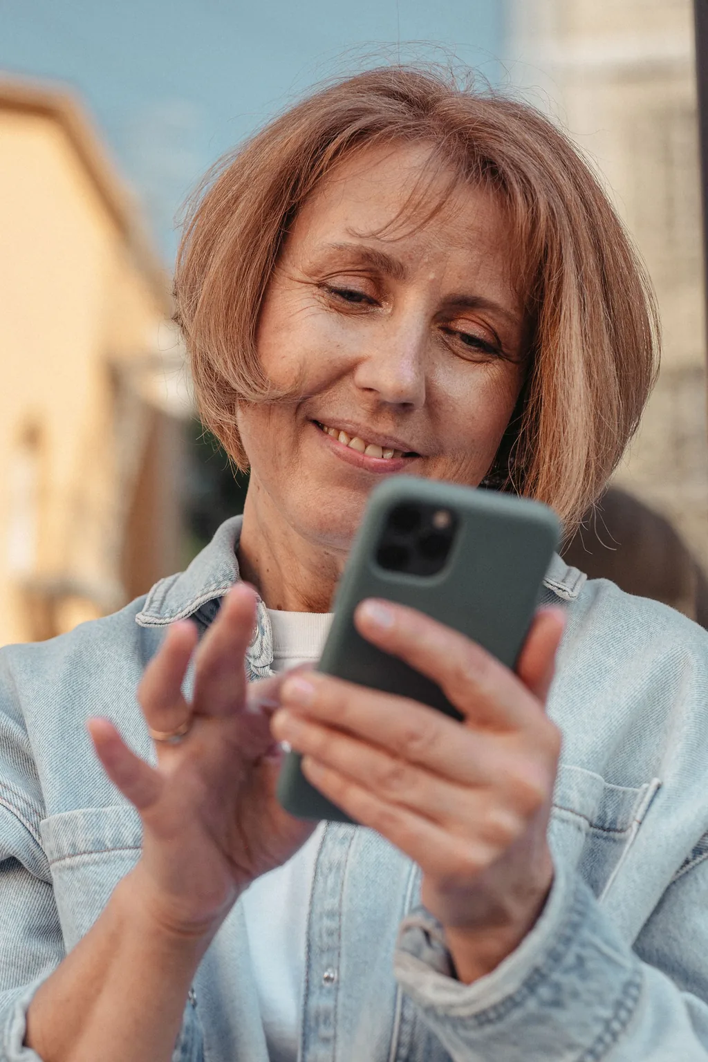 Imagen referencial: mujer sonriendo con su celular en la mano