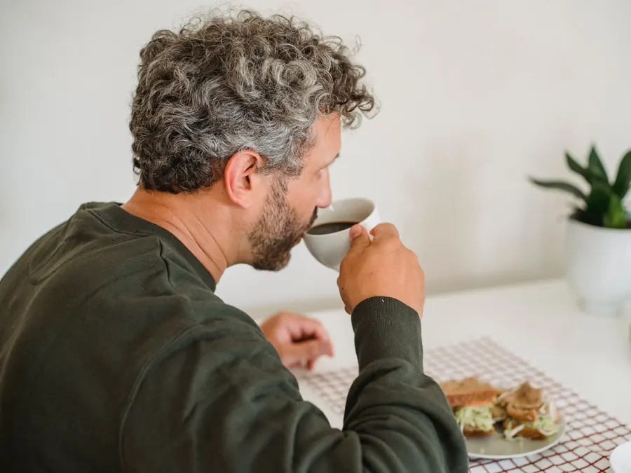 Imagen referencial: hombre tomando café en el desayuno, en la mesa de su cocina